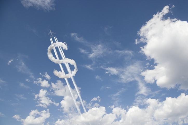 Jet trail creating dollar sign in blue sky with clouds startup capital